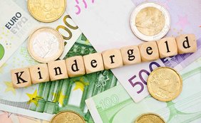Kindergeld: Ausbildung zum Rettungssanitäter ist keine Erstausbildung Euromünzen liegen auf Geldscheinen, darauf ist aus Würfeln das Wort Kindergeld gelegt