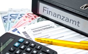 Verwertung metallischer Verbrennungsrückstände als Betriebseinnahmen eines Krematoriums Ordner mit Aufschrift Finanzamt, Taschenrechner, Geldscheine, Kugelschreiber