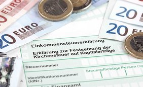 Aufzeichnungspflicht eines selbständig tätigen Steuerpflichtigen für Aufwendungen für das häusliche Arbeitszimmer Einkommensteuererklärungsformular mit Euro-Banknoten und Münzen.